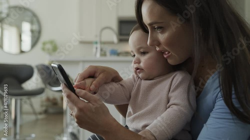 Mother teaching baby daughter to use cell phone touch screen / Bluffdale, Utah, United States photo