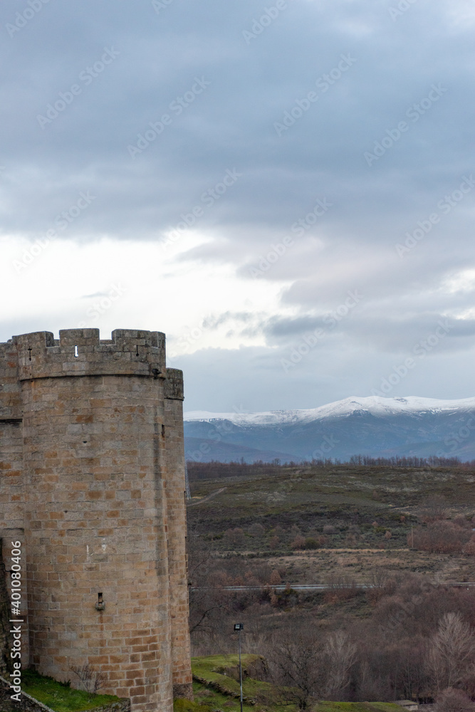 Vertical panoramic view of a stone castle tower in Puebla de Sanabria and snow-capped mountains in the background Vertical panoramic view of a stone castle tower in Puebla de Sanabria and snow-capped mountains in the background