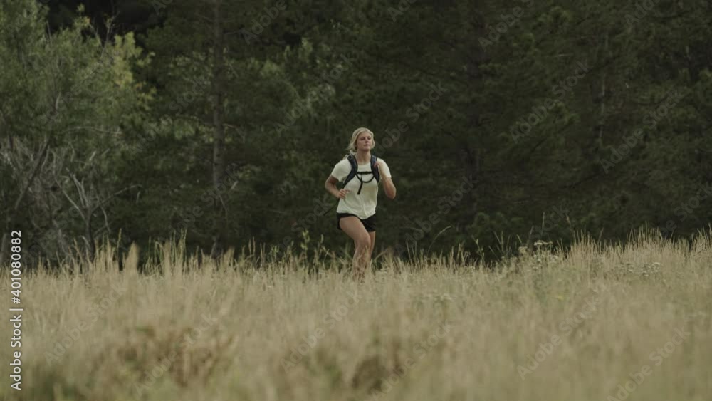 Slow motion of distant teenage girl running with backpack in field / Tibble Fork, Utah, United States Slow motion of distant teenage girl running with backpack in field / Tibble Fork, Utah, United States