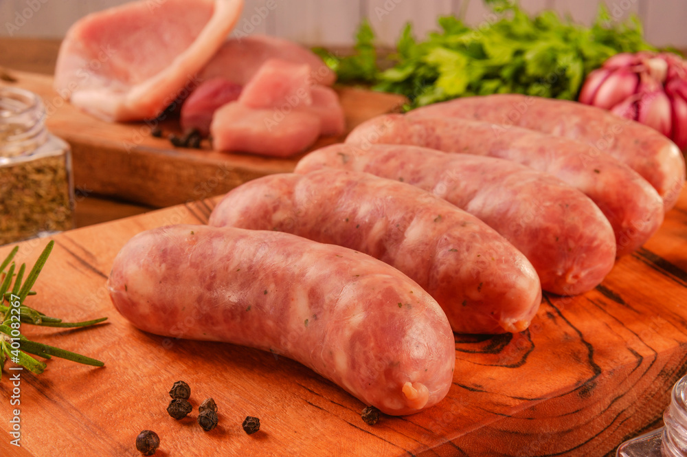 Brazilian pork leg sausage on wood cutting board with pork leg in background - Linguiça de pernil close up Brazilian pork leg sausage on wood cutting board with pork leg in background - Linguiça de pernil close up