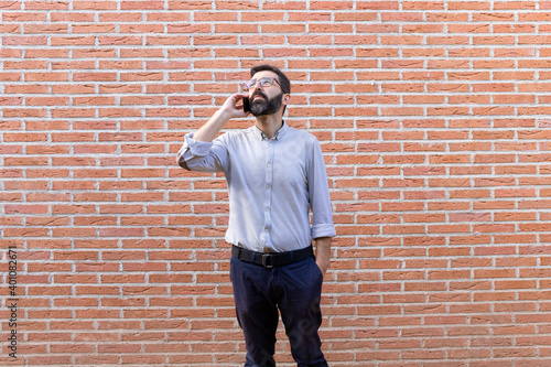 Man talking on a mobile phone. Brick wall in the background.