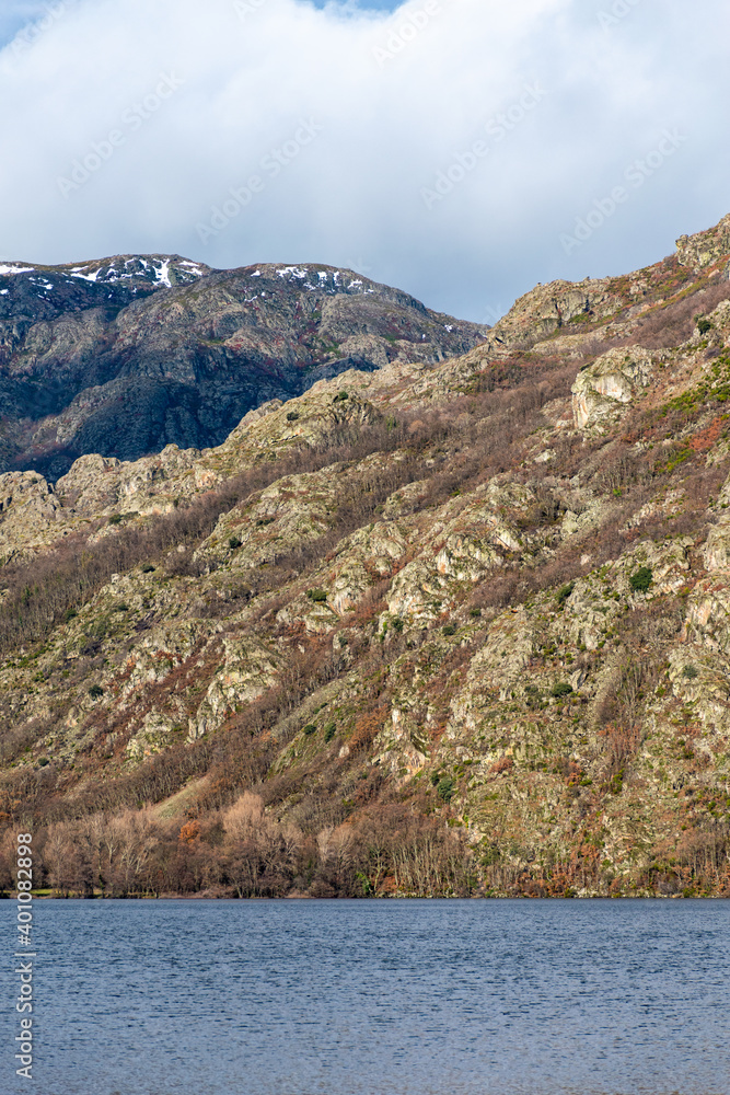 Vertical image of the glacial lake of Sanabria with the mountains on a sunny winter day with snow on the mountain top