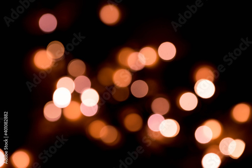 Bokeh lights background in yellow and lilac colors on black. Christmas lights string garland, festive overlay