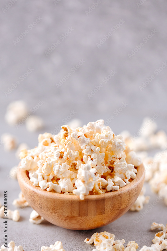 Delicios popcorn in a wooden bowl on a grey background Delicios popcorn in a wooden bowl on a grey background