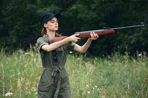 Woman on outdoor Holding a weapon in front of him hunting side views green leaves green 