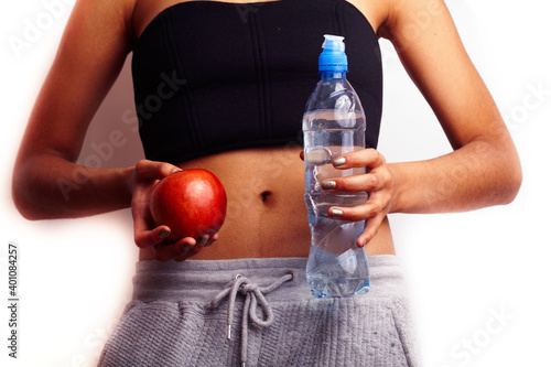 close up woman stomach with hands holding water and red apple photo