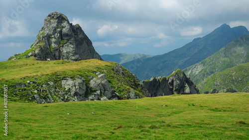 A sharp cliff pointed towards the sky standing on top of an alpine crest. Fagaras Massif provides a rocky landscape to the hiker climbing them. Carpathia, Romania.