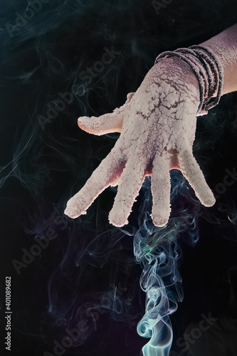 women's hands on a dark background and colored smoke