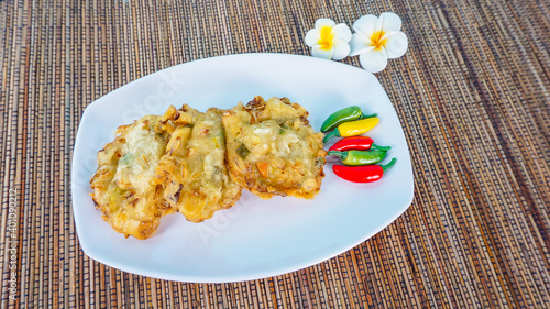 Traditional Indonesian Snack Bakwan ,vegetable fritter made from corn, carrot and cabbage served with red chili on wricker background photo