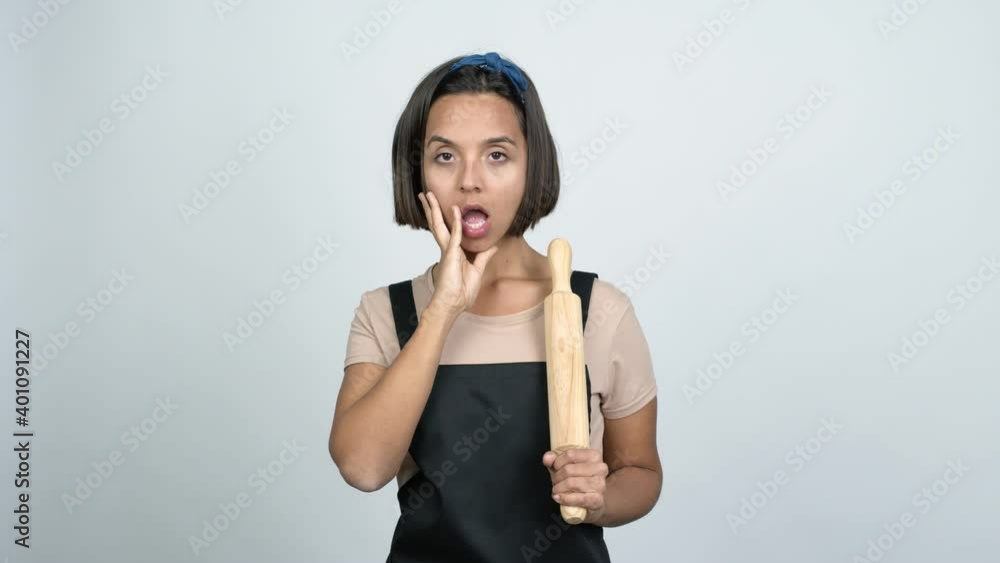 Young latin woman holding a rolling pin gaping because have just surprised with a gift over isolated background Young latin woman holding a rolling pin gaping because have just surprised with a gift over isolated background
