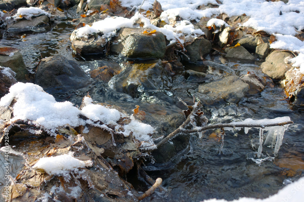 Partially frozen and snow covered creek in beautiful prír with icicles