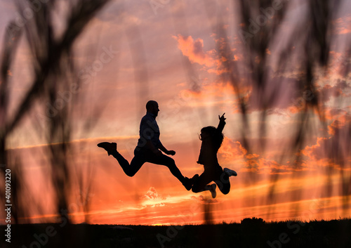 Fotografía Pareja en silueta saltando de alegría al atardecer