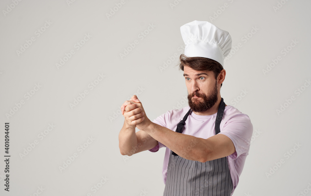 A cook in a headdress is gesturing with his hands on a light background, success emotions A cook in a headdress is gesturing with his hands on a light background, success emotions
