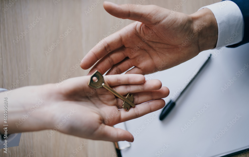 handing the key from hand to hand to the office business finance work documents