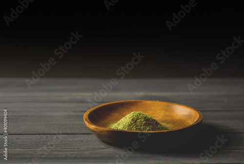 Mitragynina speciosa or Kratom powder in wooden bowl on table photo