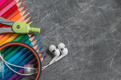 multicolored school supplies lie on black chalkboard, short focus, partial blur