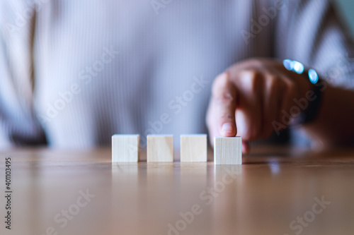 Closeup image of a hand choosing and picking a blank wooden cube block