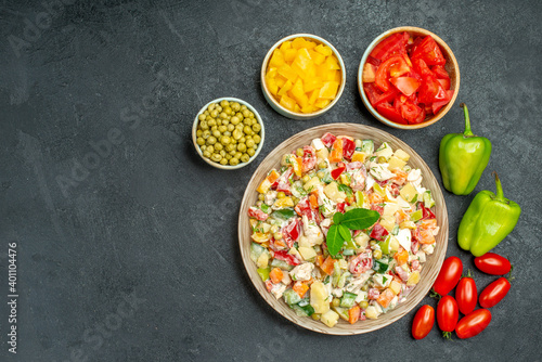 top view of vegetable salad with different vegetables on side with free space for text on the left side on the grey background