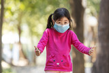 Lovely little girl makeing sign of  joyfully when they wearing medical   face and playing at the park for reduce infection of coronavirus covid-19 pandemic.New normal lifestyle.