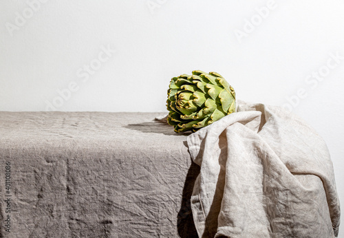 Artichoke on the table covered with a gray linen tablecloth. photo