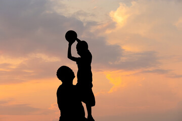 Silhouette of father and son with ball evening sky sunset background, Sport and enjoying life concepts.