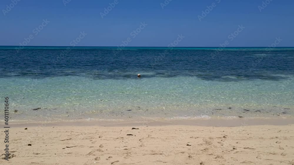 Aerial Low Flying Above Sandy Beach Towards Yellow Buoy Floating Nearby In Waters. Follow Shot Aerial Low Flying Above Sandy Beach Towards Yellow Buoy Floating Nearby In Waters. Follow Shot