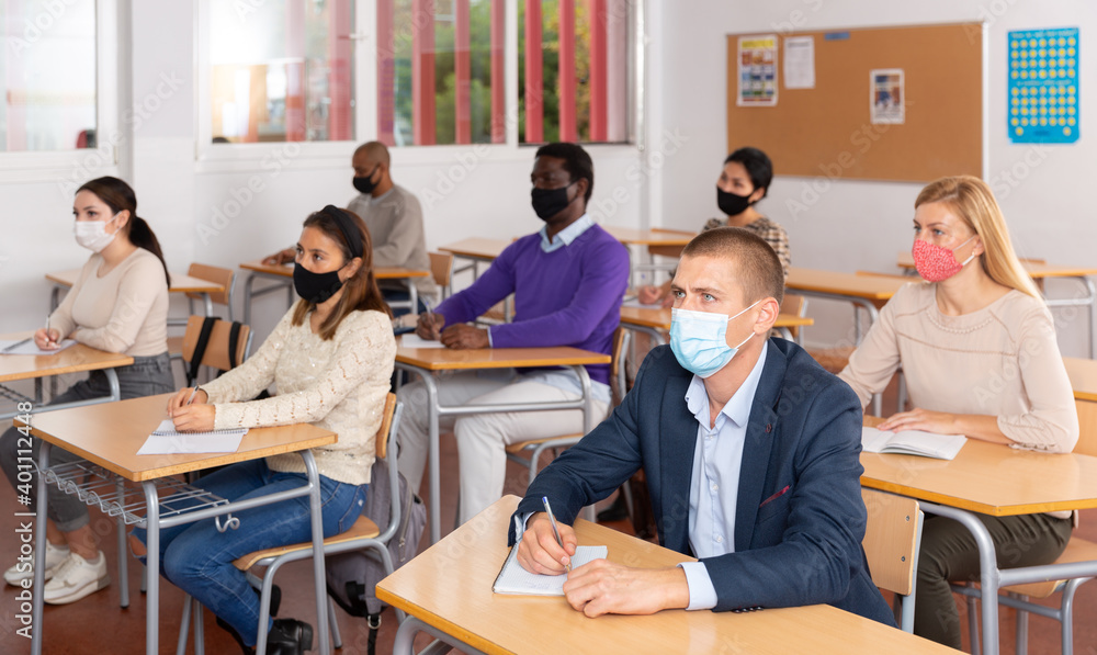 Portrait of adult man in medical face mask during lesson in extension school. Concept of necessary precautions and social distancing in coronavirus pandemic