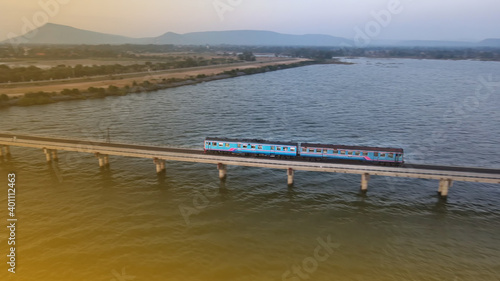 Aerial view of Thailand passengers train running on the floating railway bridge during sunset in the lake of 