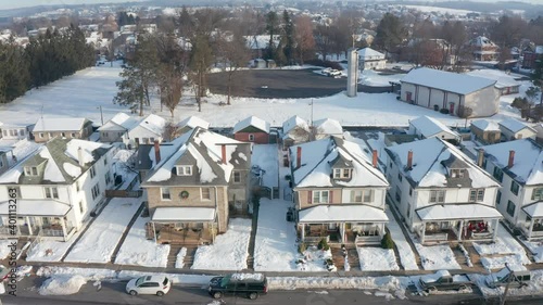 Establishing shot of large houses in United States, homes line small town street in America, USA housing residential community neighborhood during winter. Aerial snow drone view.