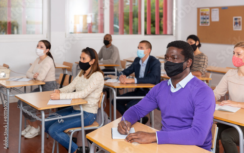 African-american student wearing protective mask among students in university classroom © JackF