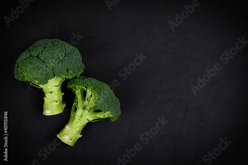 Healthy green organic raw broccoli florets on black background