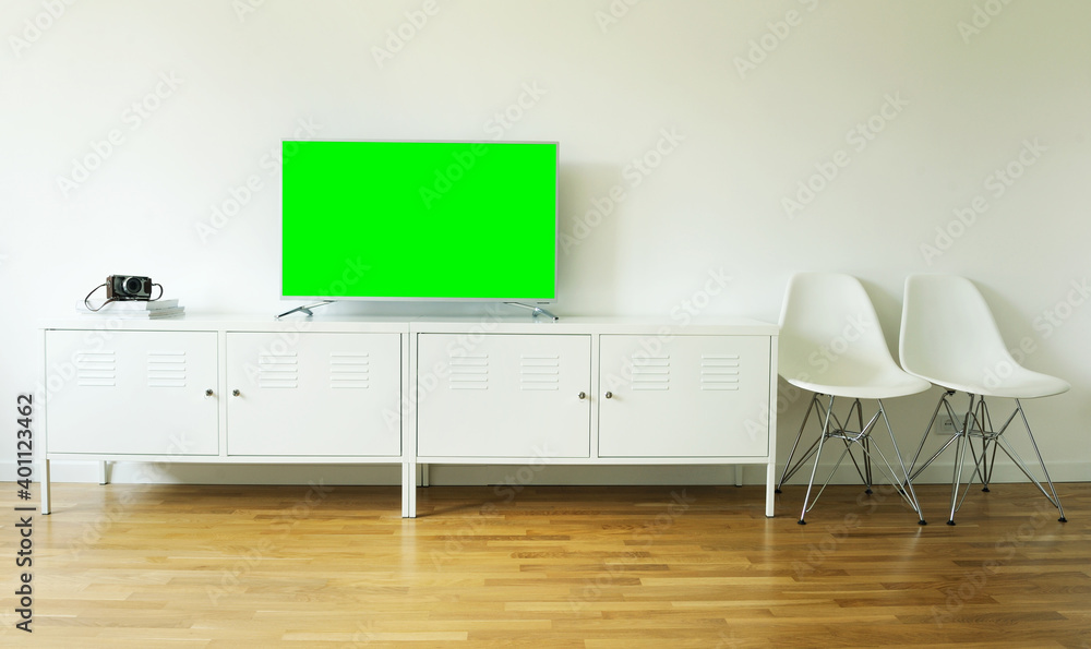 Naklejka premium Widescreen modern green screen TV for text and video on a chrome stand against a white wall.