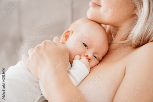 mom is mom is lying down with a baby in a white bed after feeding breast milk. 