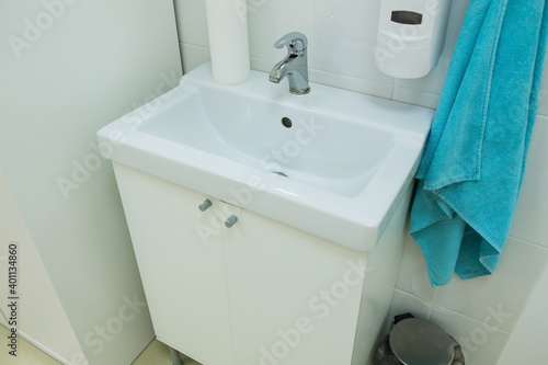 White sink in hospital room with liquid soap and medical things. Equipment for maintaining cleanliness and sterility in the hospital.