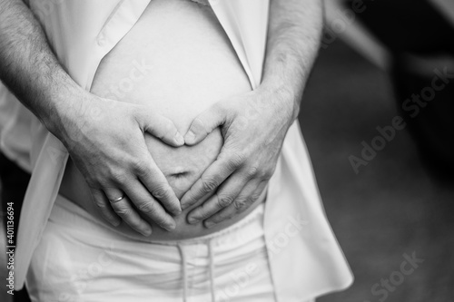 black-white. men hands on the belly of a pregnant woman.