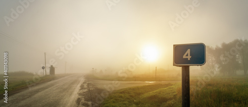Blue road sign with number 4 at the cross in the foggy sunrise
