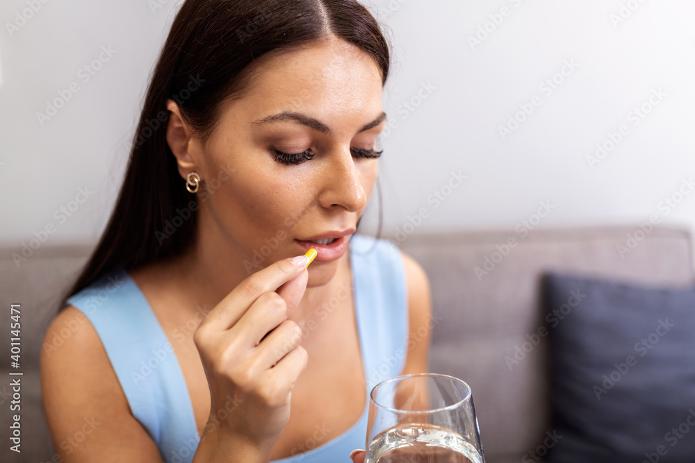 Depressed woman holding pill and glass of water taking painkiller to relieve pain, medicine supplements vitamins, antibiotic medication, meds for old person concept, close up view Depressed woman holding pill and glass of water taking painkiller to relieve pain, medicine supplements vitamins, antibiotic medication, meds for old person concept, close up view