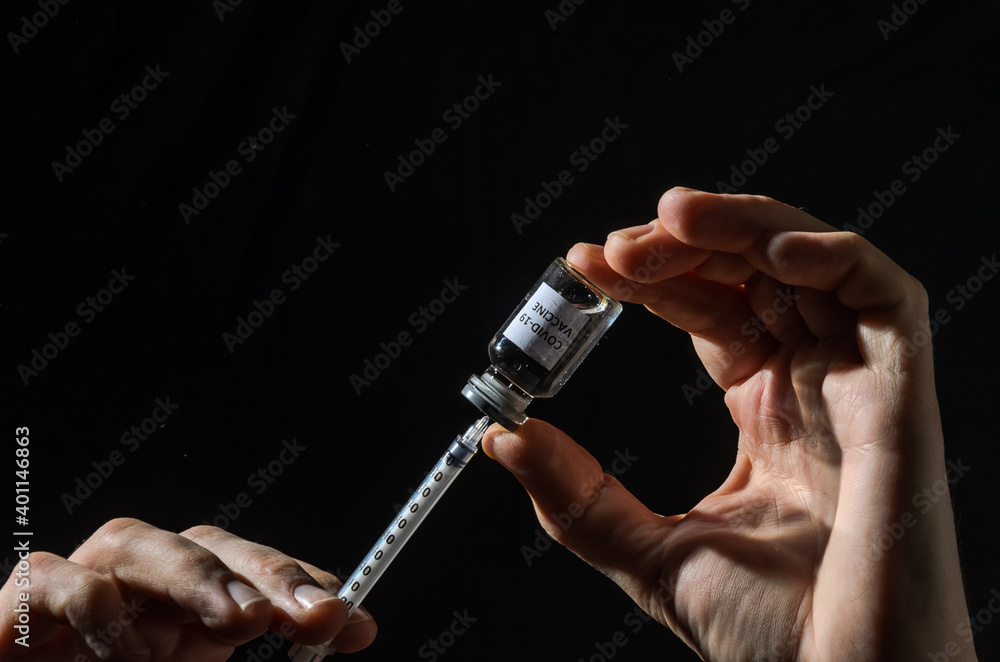 Ampoule with covid-19 vaccine and syringe for injection on black background	
