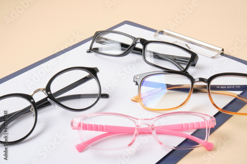 glasses on a clipboard, beige background, diagnostics of vision