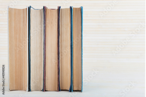 Some old books standing vertically light background.Five volumes is on the table.Selective focus.Copy space.Concept of learning and reading.