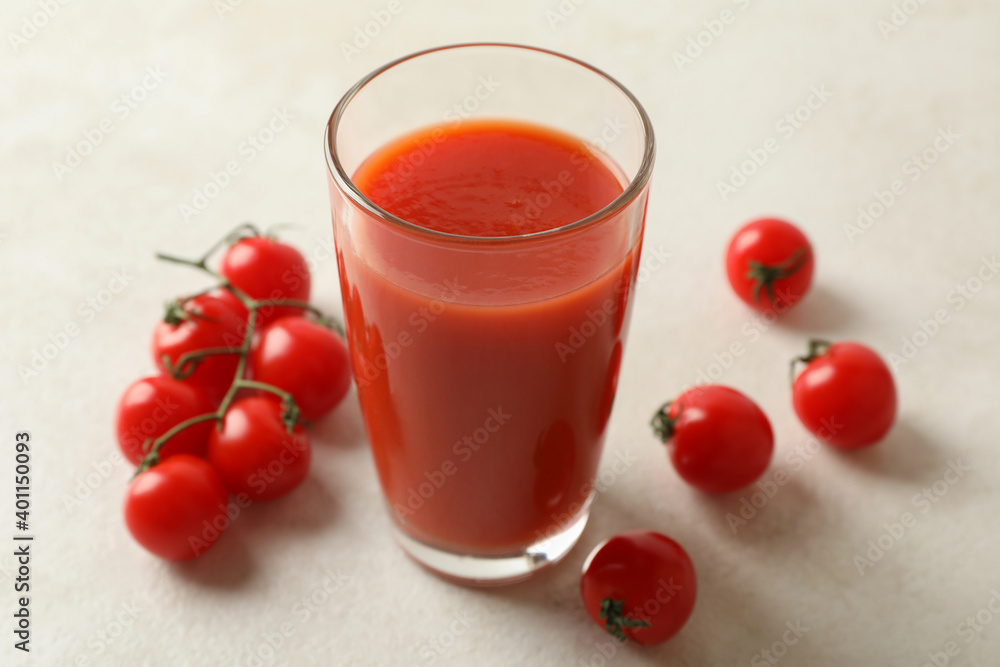 Glass of tomato juice and tomatoes on white textured background Glass of tomato juice and tomatoes on white textured background