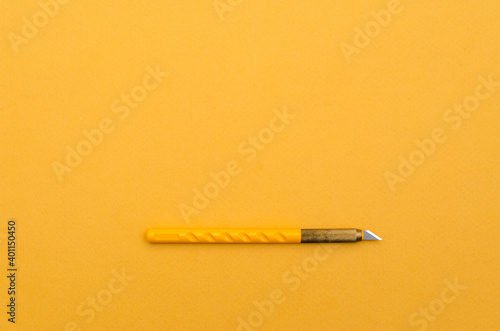 Stationery paper knife on blank colored paper. Place for text. Top view.