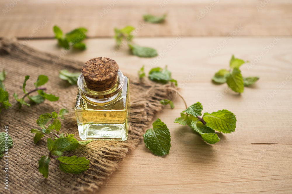 Peppermint Essential oil in glass bottle with mint leave on wood background. herb or aromatherapy spa concept. Peppermint Essential oil in glass bottle with mint leave on wood background. herb or aromatherapy spa concept.