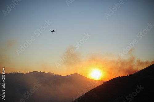 Airplane at the sunset flying over the mountains
