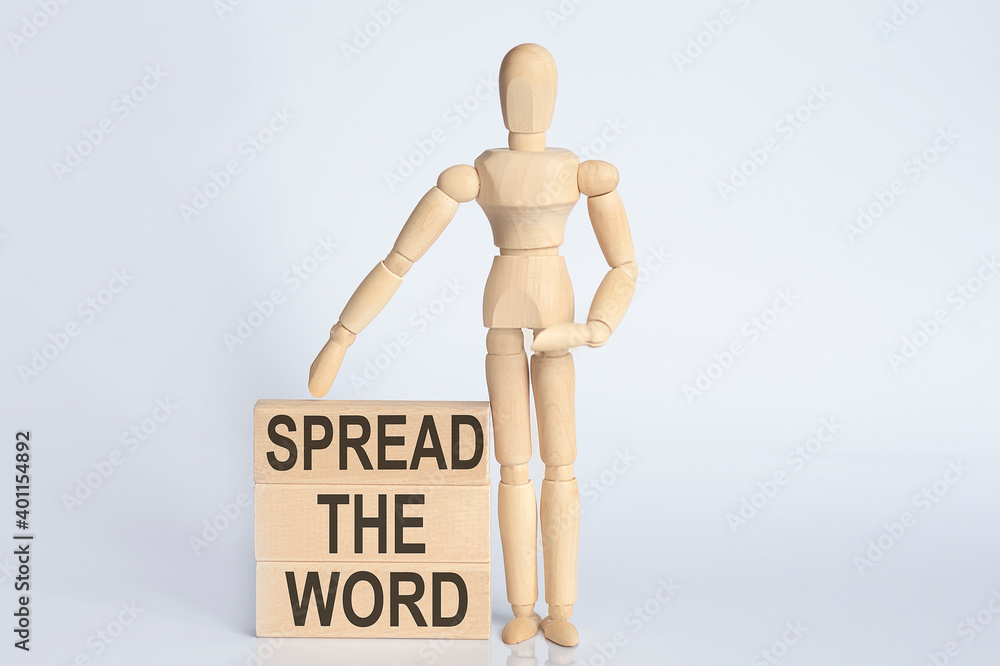 Wooden man shows with a hand text SPREAD THE WORD concept on wooden block Wooden man shows with a hand text SPREAD THE WORD concept on wooden block