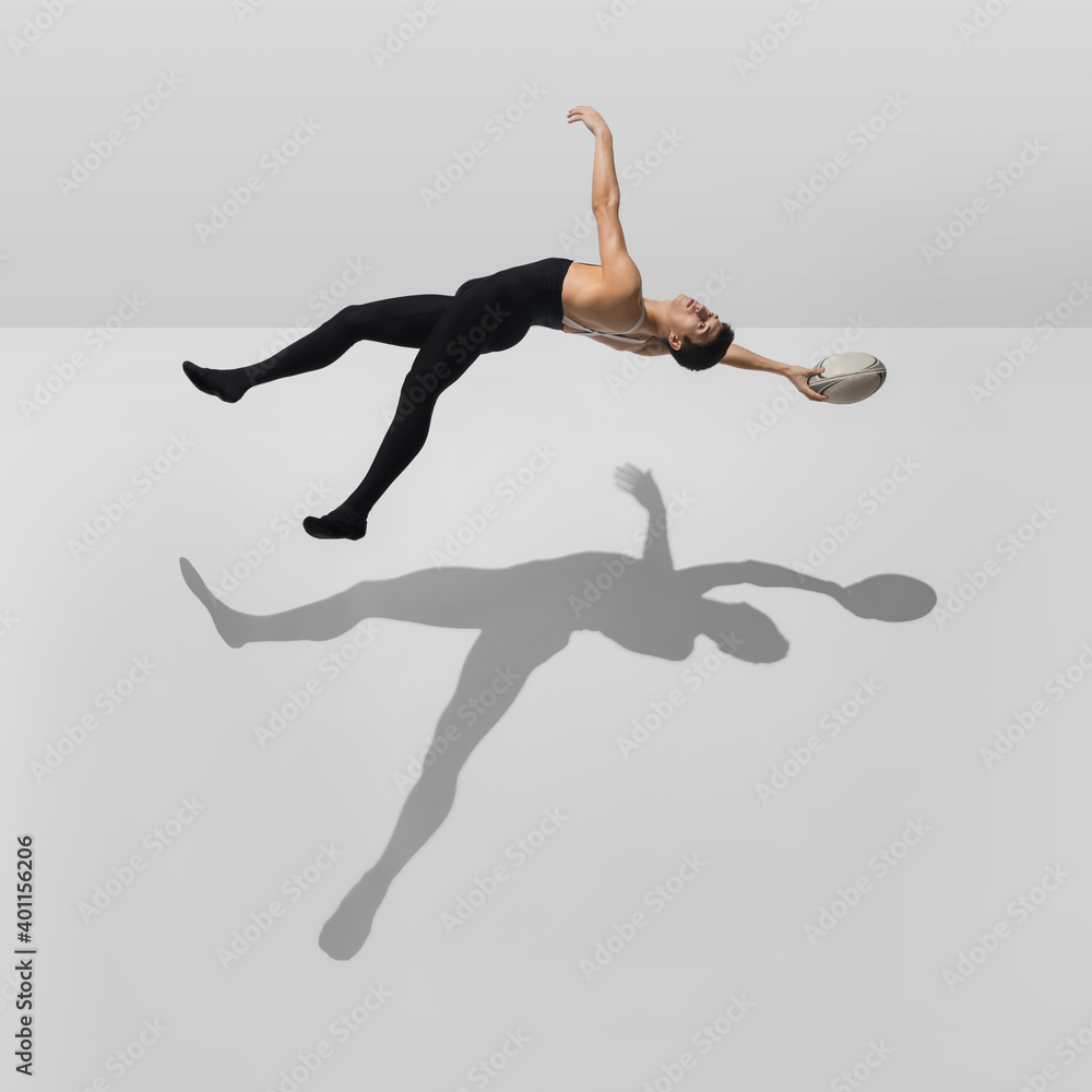 Fototapeta premium Inspiration. Stylish young male athlete on white studio background with shadows in jump, air flying. Sportive fit model in motion and action. Body building, healthy lifestyle, style concept.