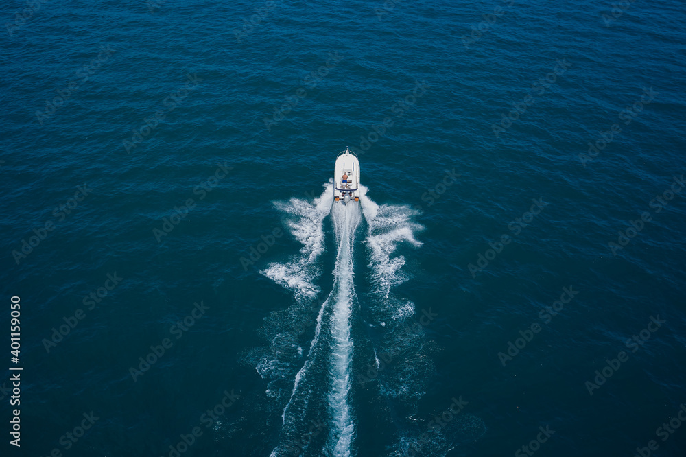 Obraz premium Aerial bird's eye view photo taken by drone of boat. Top view of a white boat sailing to the blue sea. Motor boat in the sea.Travel - image.