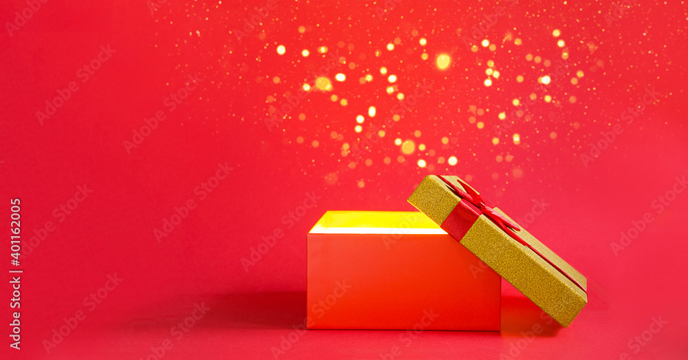 Open red gift box with a bow with a golden glow and glitter inside on a red background, banner, copyspace. universal holiday, christmas, valentine's day, new year, birthday, anniversary, present Open red gift box with a bow with a golden glow and glitter inside on a red background, banner, copyspace. universal holiday, christmas, valentine's day, new year, birthday, anniversary, present