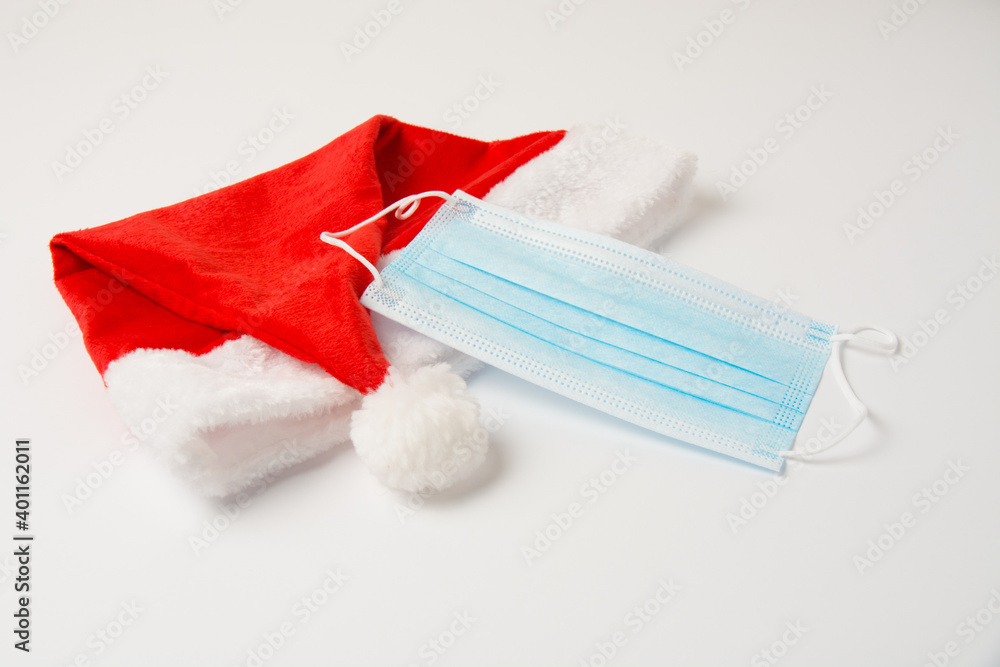 Santa hat and medical mask on white background close up with copy space Santa hat and medical mask on white background close up with copy space