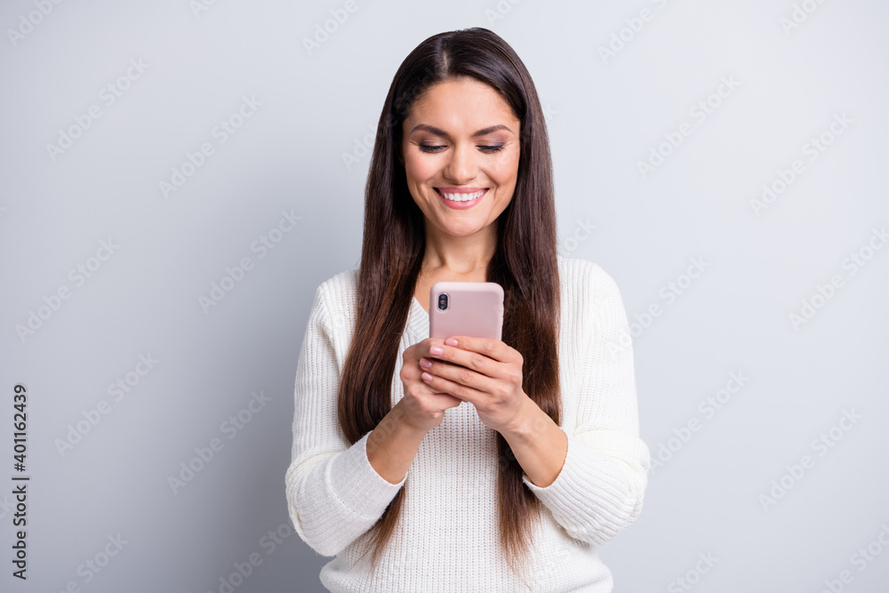 Photo of mature pretty beautiful smiling happy cheerful woman using smartphone isolated on grey color background Photo of mature pretty beautiful smiling happy cheerful woman using smartphone isolated on grey color background